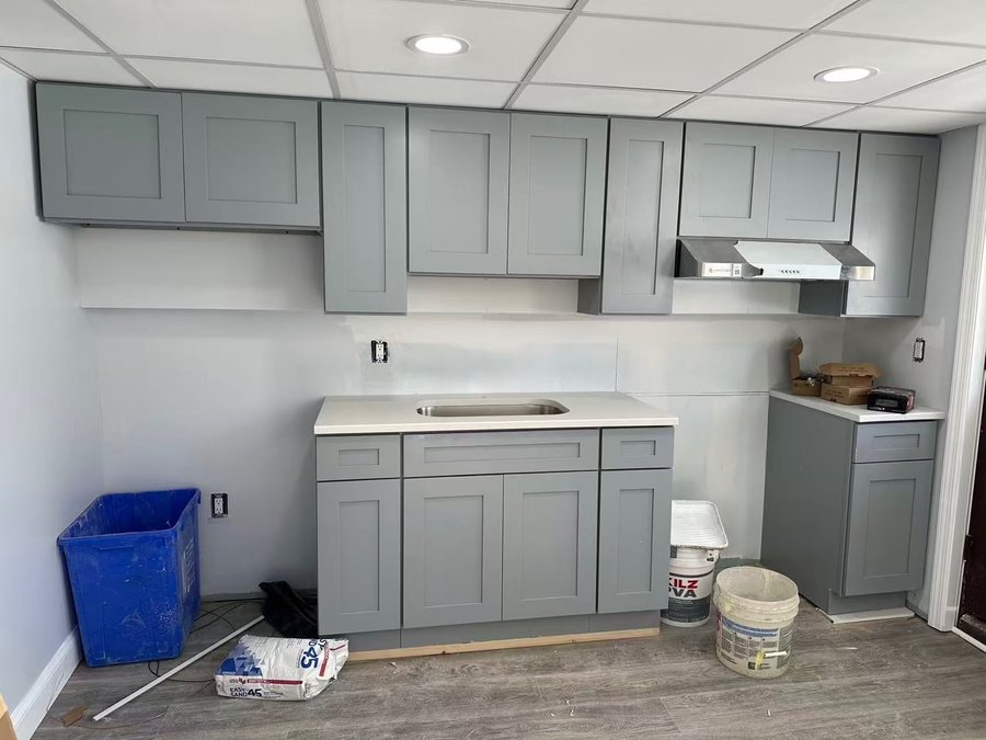 Gray Shaker cabinets installed with a white counter and a stainless hood, backsplash not yet on
