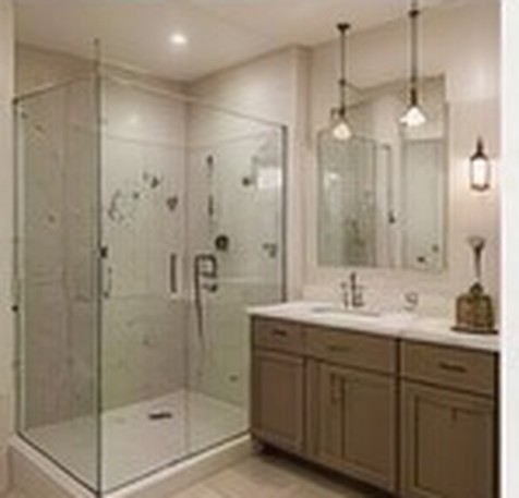 Design view of the primary bathroom with a glass walk in shower and twin vanity