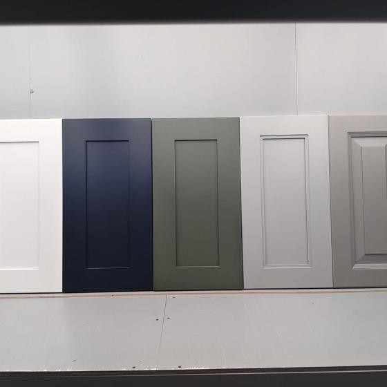 Cabinet doors in five finishes lined up against a wall
