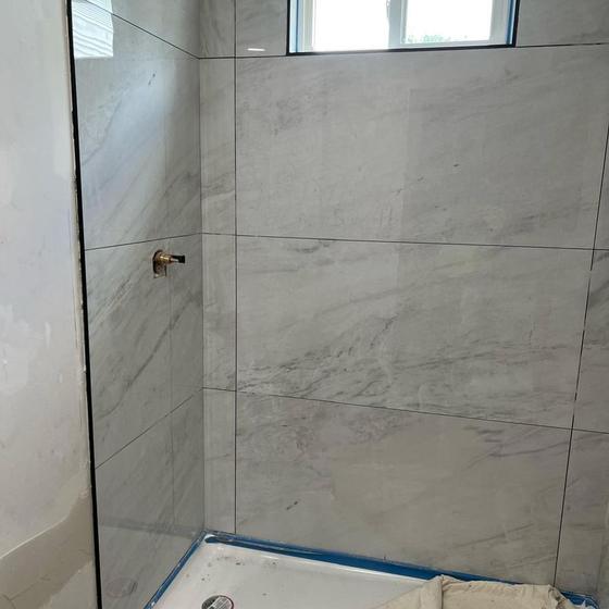 Marble look shower wall with a tiled window opening