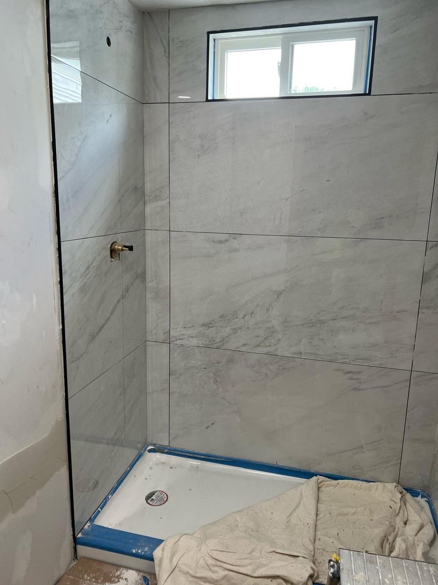 Marble tiled shower with the window trimmed in, on one of our bathroom jobs